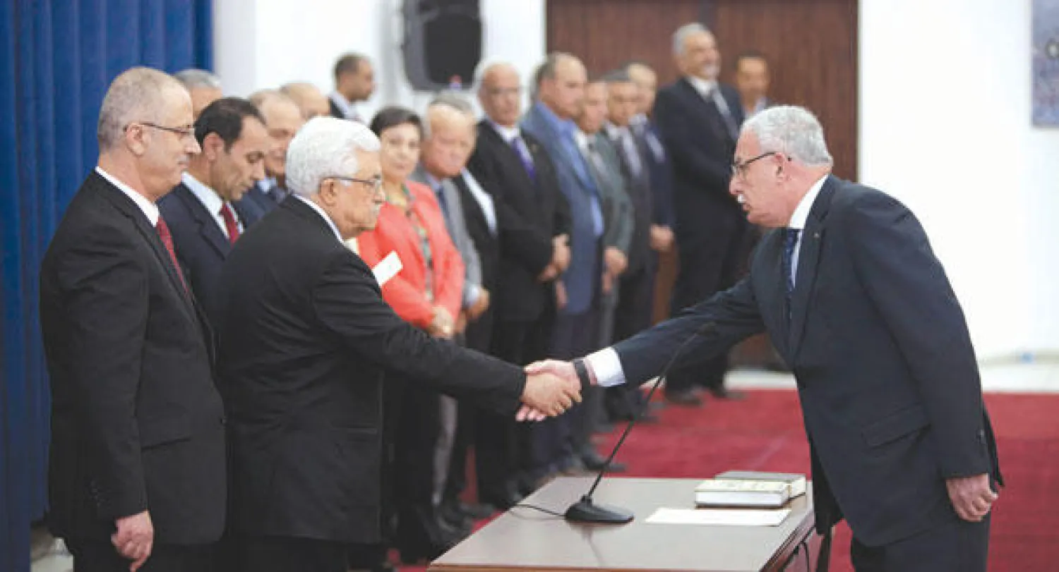عباس يصافح وزير الخارجية خلال تأدية حكومة التوافق الفلسطينية اليمين أمامه في رام الله أمس (أ.ب)