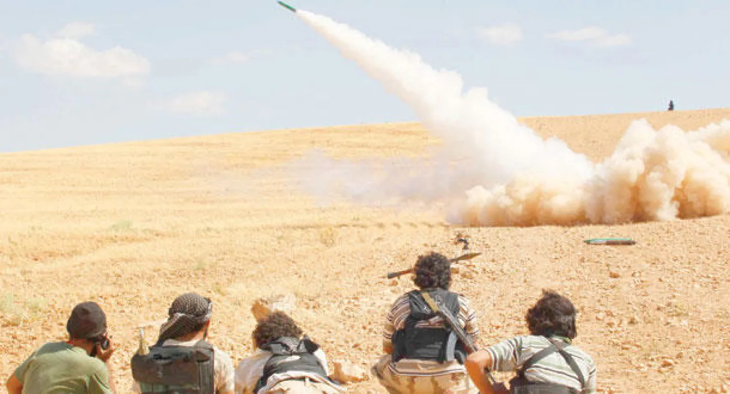 عناصر من الجيش السوري الحر خلال إطلاقهم صاروخا على القوات الحكومية في ريف حماه أمس (رويترز)