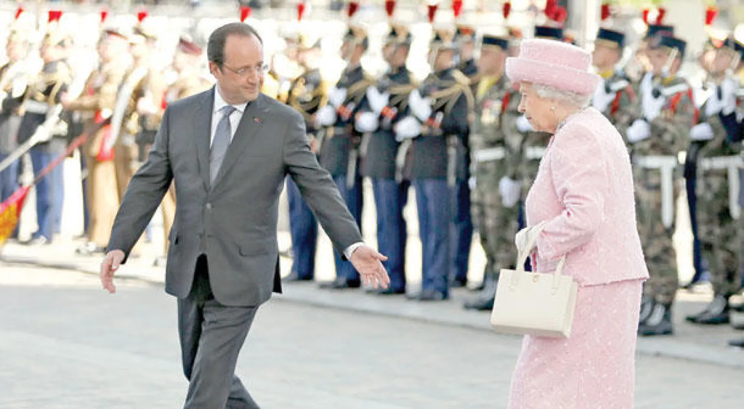 الملكة إليزابيث الثانية مرفوقة بالرئيس الفرنسي فرنسوا هولاند أثناء وصولها للمشاركة في حفل وضع إكليل من الزهور في قوس النصر بباريس أمس (إ.ب.أ)