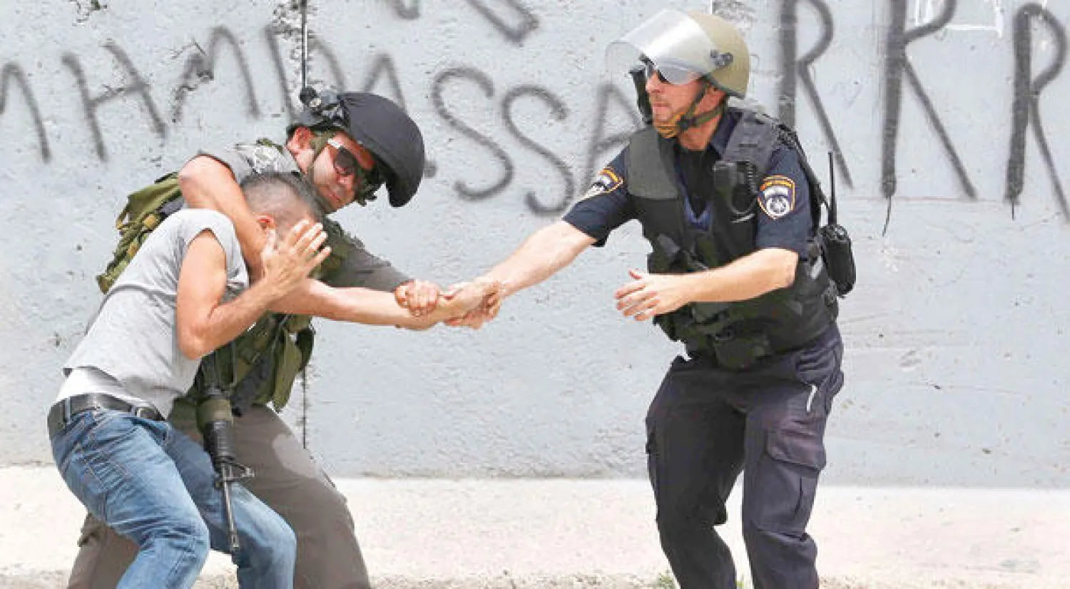 عنصران من الشرطة الإسرائيلية يقبضان على فلسطيني خرج في احتجاج تضامنا مع السجناء المضربين عن الطعام في رام الله أمس (رويترز)