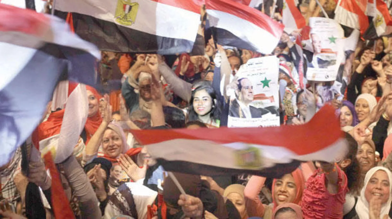 مصريون يواصلون احتفالاتهم بفوز الرئيس المنتخب عبد الفتاح السيسي بالانتخابات الرئاسية ويرفعون الأعلام الوطنية والملصقات المؤيدة له أمام قصر الاتحادية الرئاسي  (أ.ف.ب)