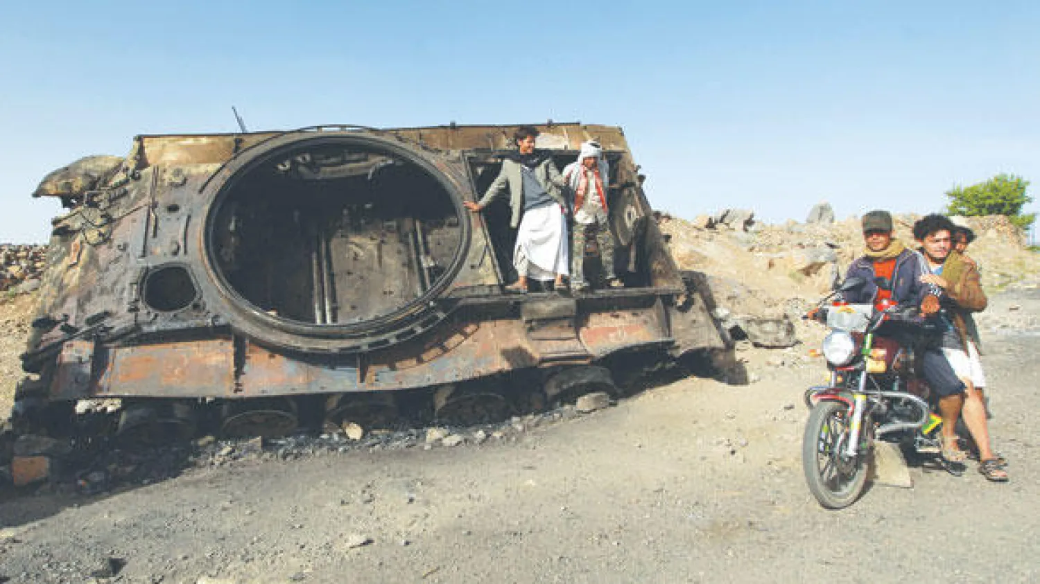 يمنيون يشاهدون الدمار الذي لحق بإحدى دبابات الجيش اليمني في عرمان أمس ( أ. ف. ب)