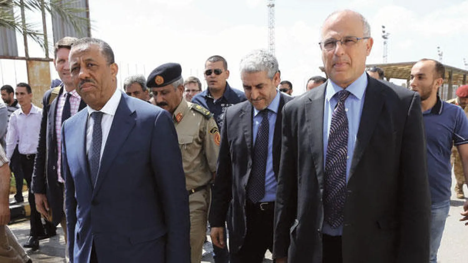 رئيس الوزراء الليبي عبد الله الثني والسفير البريطاني مايكل آرون ورئيس أركان القوات المسلحة الليبية اللواء عبد السلام جاد الله (خلف) خلال وداعهم لدفعة من ضباط وضباط صف وأفراد من الجيش الليبي المتجهين الى بريطانيا للمشاركة في دورة تدريبية، في مطار معيتيقة الدولي أمس (أ.ف.ب)