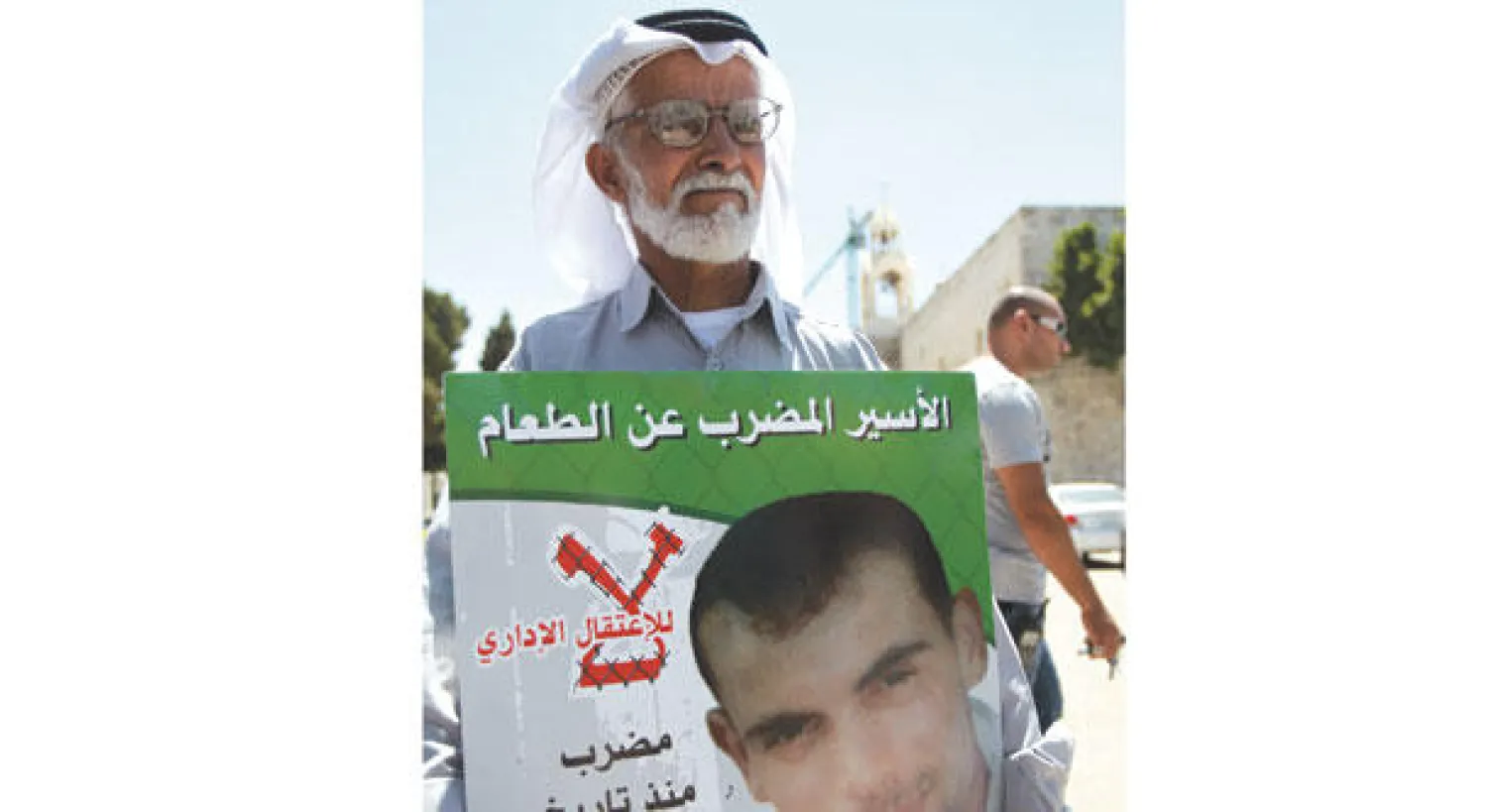 فلسطيني يحمل صورة أسير مضرب عن الطعام خلال مظاهرة في بيت لحم بالضفة الغربية أمس (أ.ف.ب)