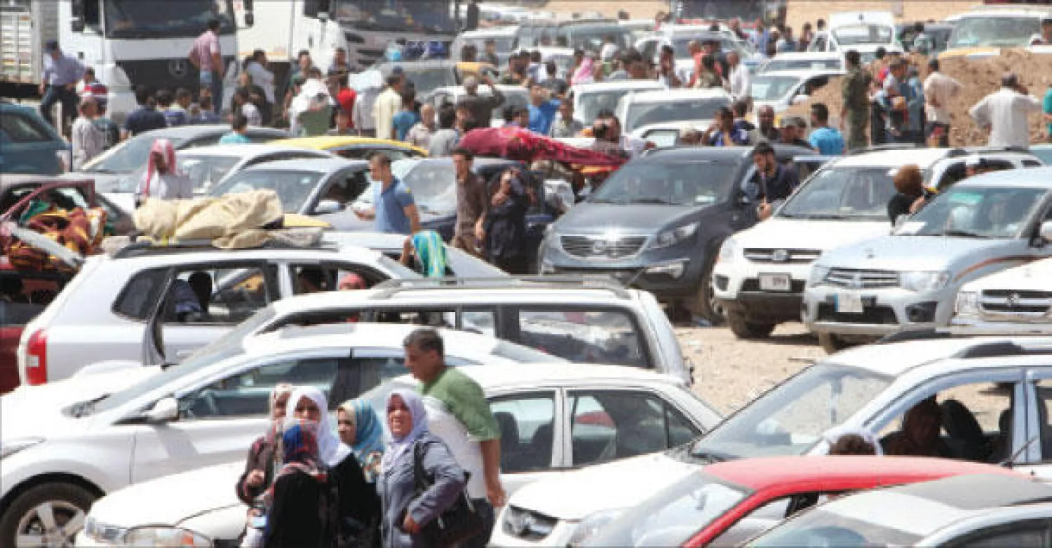 عائلات نازحة من مدينة الموصل تنتظر عند نقطة عبور إلى إقليم كردستان أمس (رويترز)