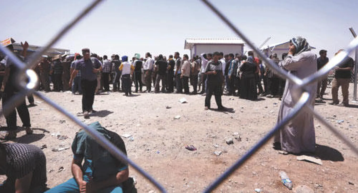 عائلات نازحة من محافظة نينوى تقف عند نقطة تفتيش رئيسة في انتظار الدخول إلى إقليم كردستان أمس (أ.ف.ب)