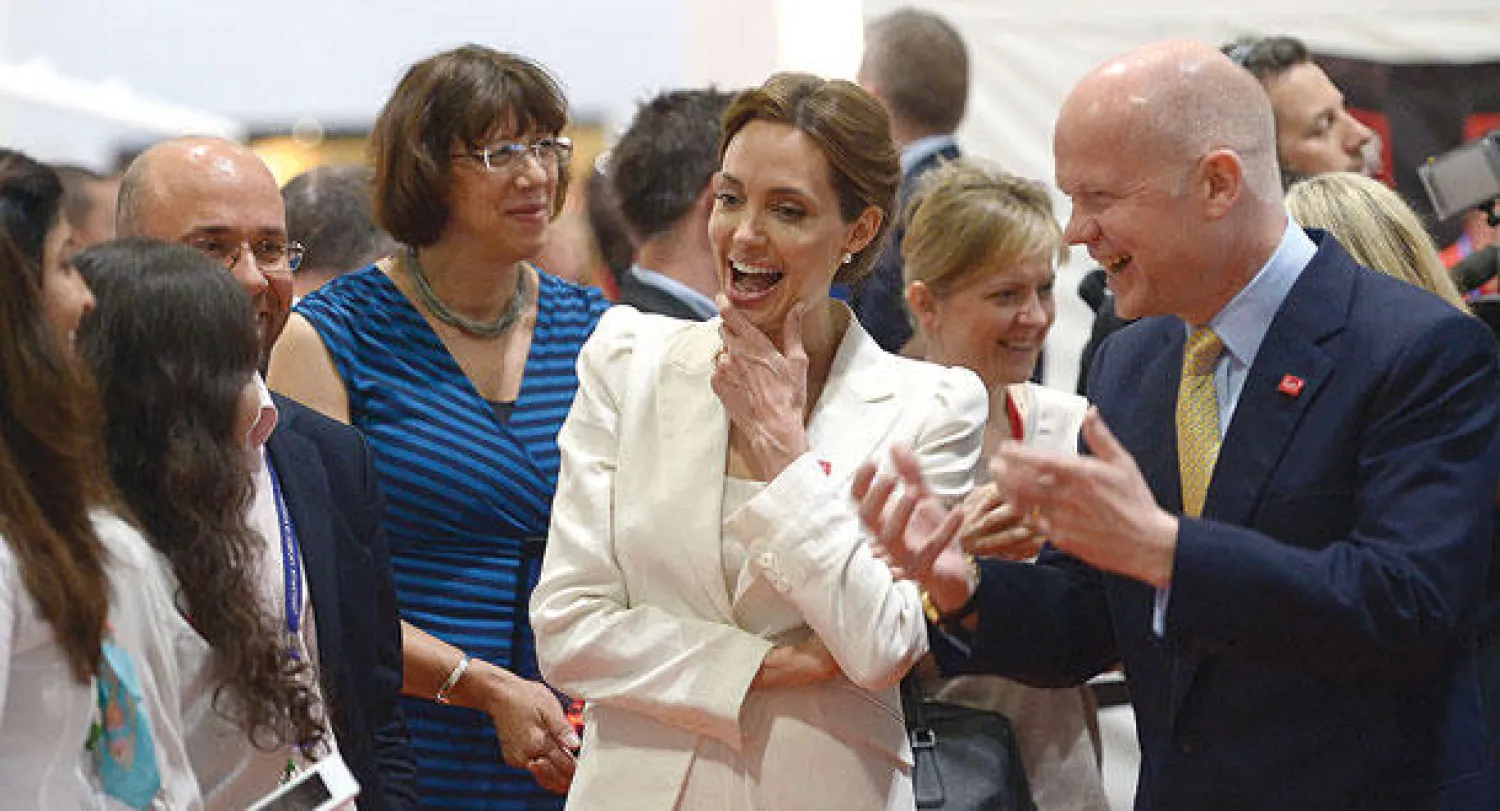 الممثلة أنجلينا جولي ووزير الخارجية البريطاني وليام هيغ يتحدثان مع مشاركين في قمة لندن أمس (أ.ف.ب)