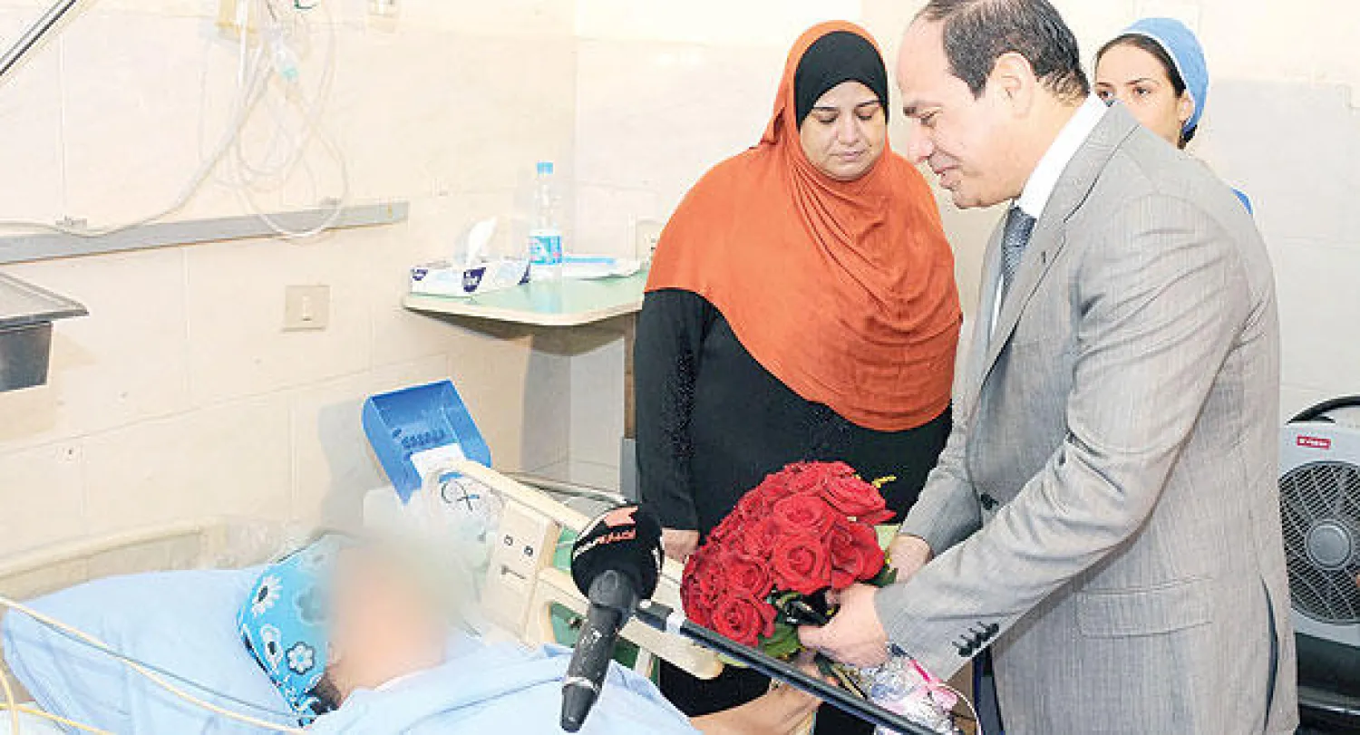 الرئيس المصري عبد الفتاح السيسي خلال زيارته أمس للسيدة ضحية التحرش التي أخفت  وسائل الإعلام وجهها في أحد المستشفيات العسكرية شرق القاهرة (أ.ف.ب)