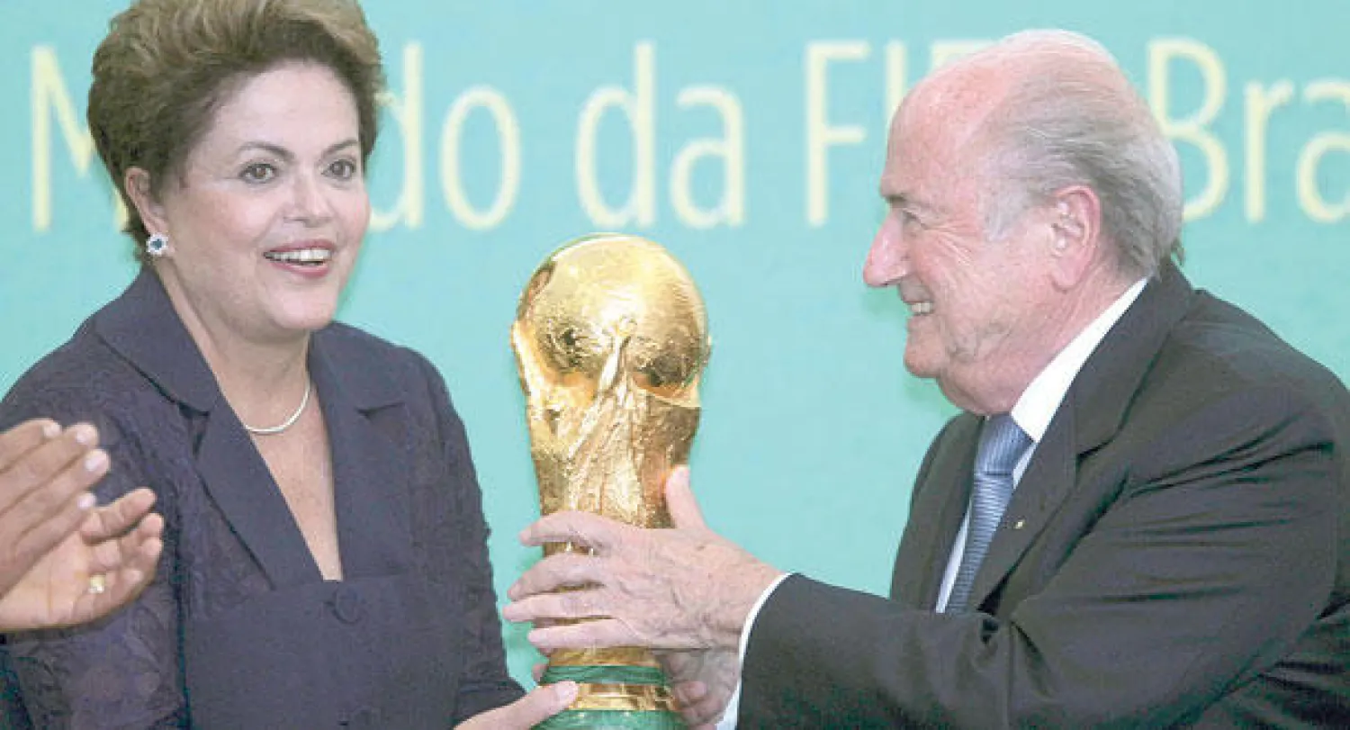 روسيف رئيسة البرازيل وبلاتر رئيس الفيفا يضعان كأس العالم في مقر الاتحاد البرازيلي (رويترز)