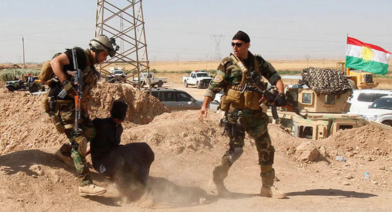 عنصران في  البيشمركه الكردية يقتادان رجلا يشتبه في انتمائه إلى «داعش» اعتقل خلال اشتباكات في ضواحي كركوك أمس (رويترز)