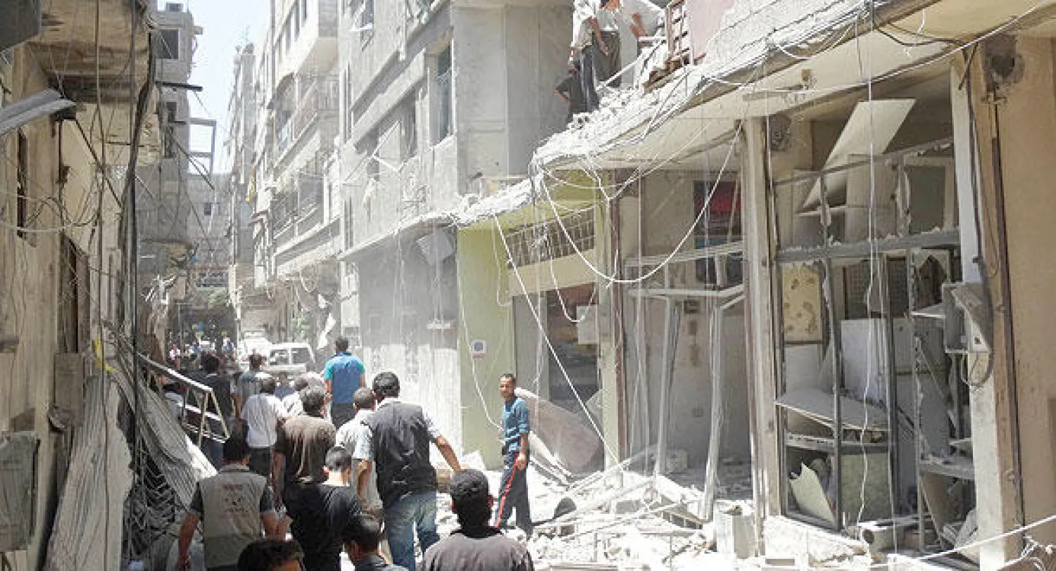 سوريون يعاينون الدمار بعد غارة جوية في بلدة سقبا بريف دمشق أمس (رويترز)