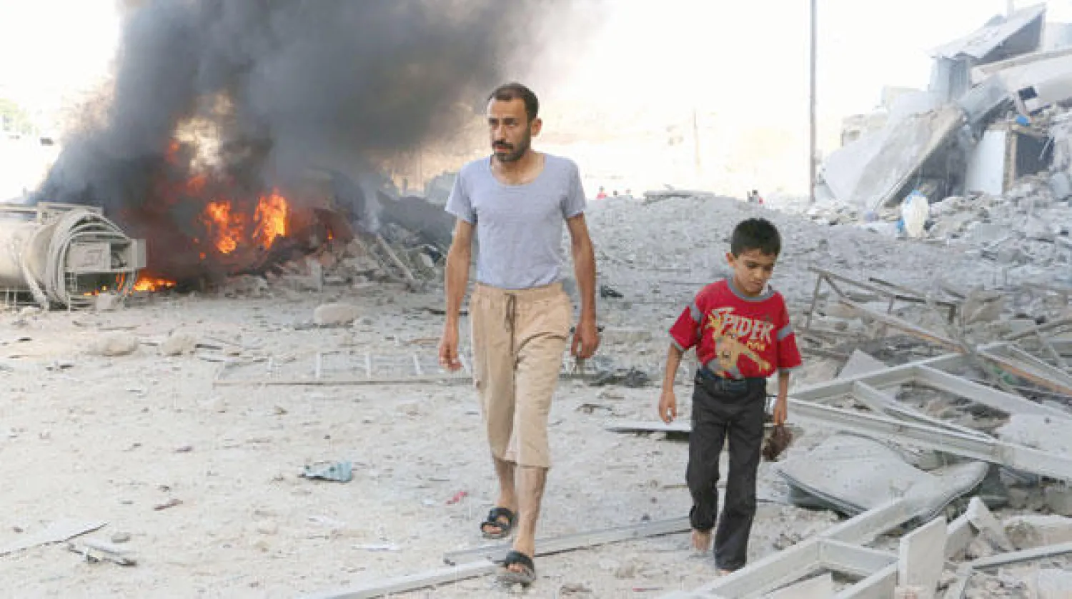 سوري مع إبنه بالقرب من منازل دمرتها صواريخ طائرات النظام السوري في حلب أمس (أ.ف.ب)