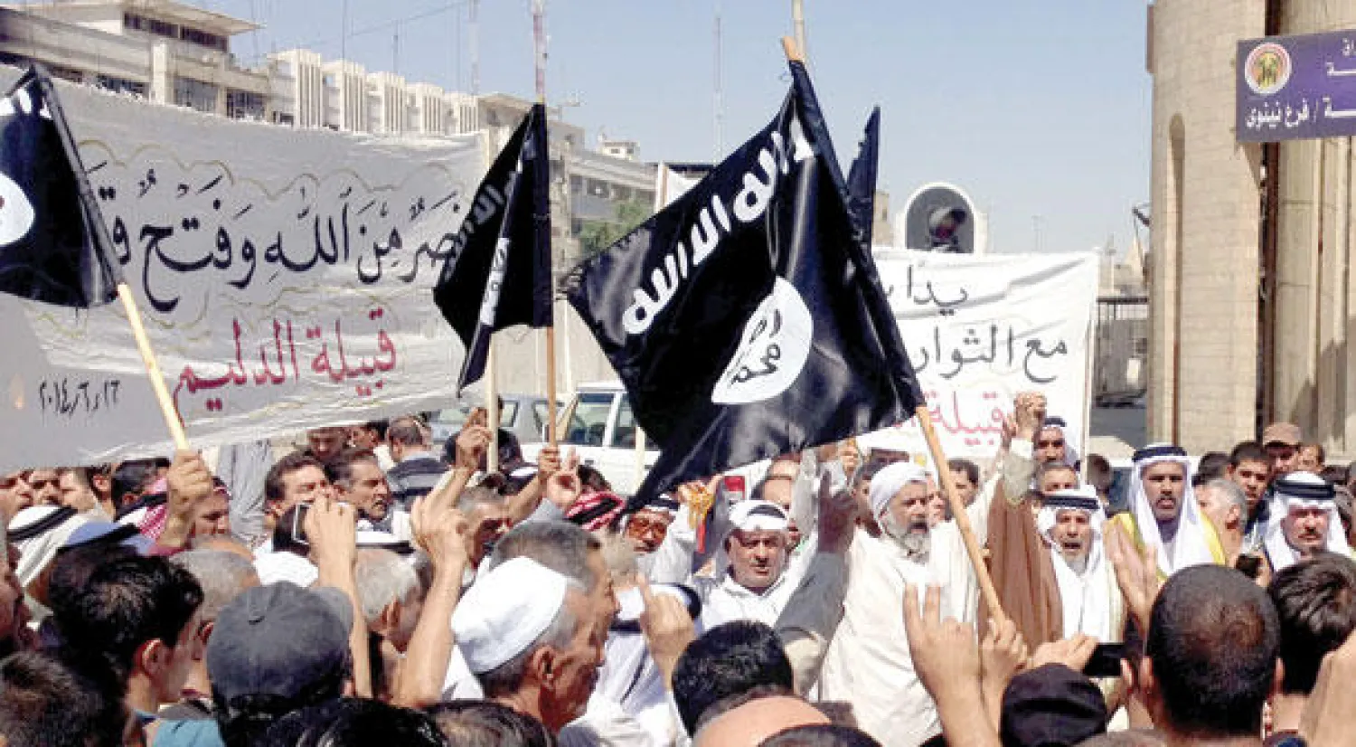 مؤيدون لتنظيم داعش يرفعون علم القاعدة شمال غرب بغداد أمس (أ.ب)