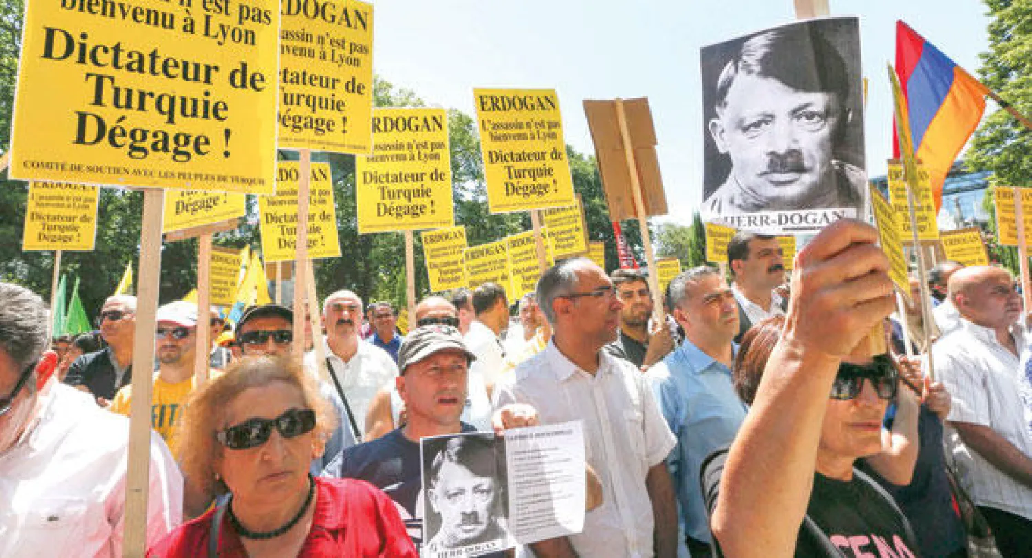 متظاهرون أتراك يرفعون صورة لإردوغان وقد تحول إلى هتلر في مدينة ليون الفرنسية أمس (رويترز)