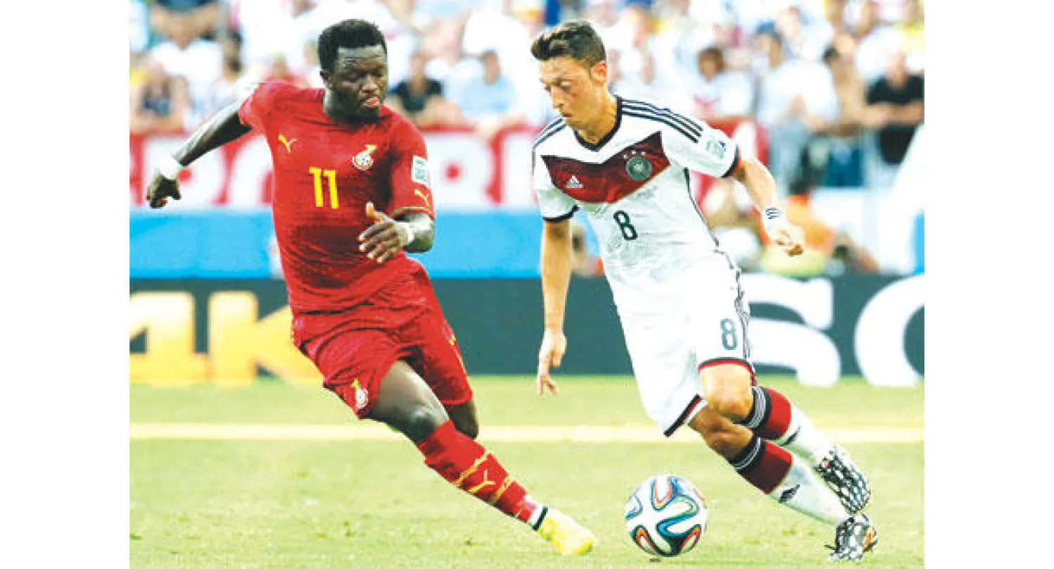 أوزيل يقود إحدى الهجمات الألمانية وسط مضايقة الغاني مونتاري (إ.ب.أ)