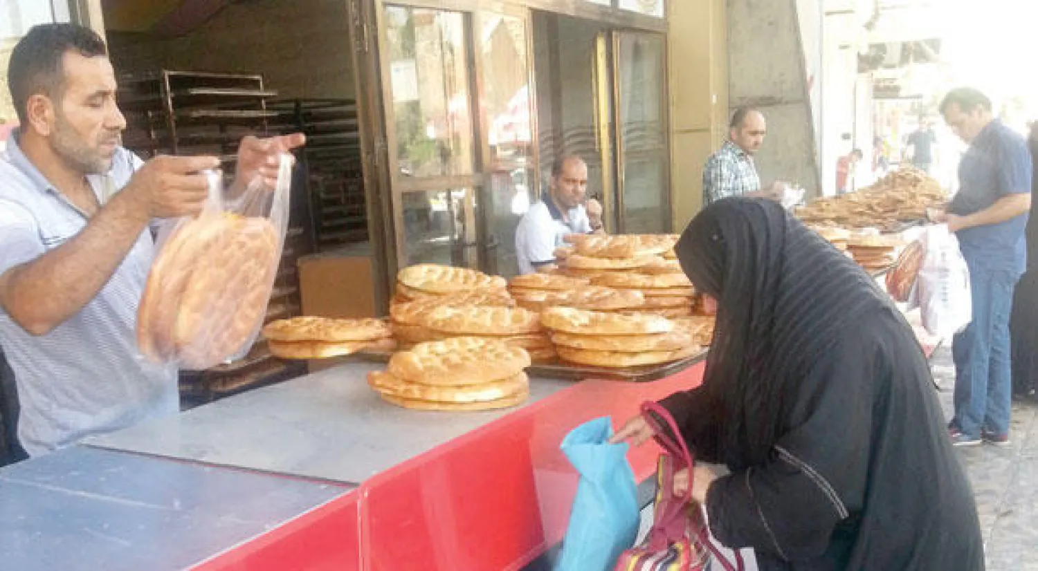 عراقية تشتري خبزا من أحد مخابز الموصل أول من أمس (رويترز)