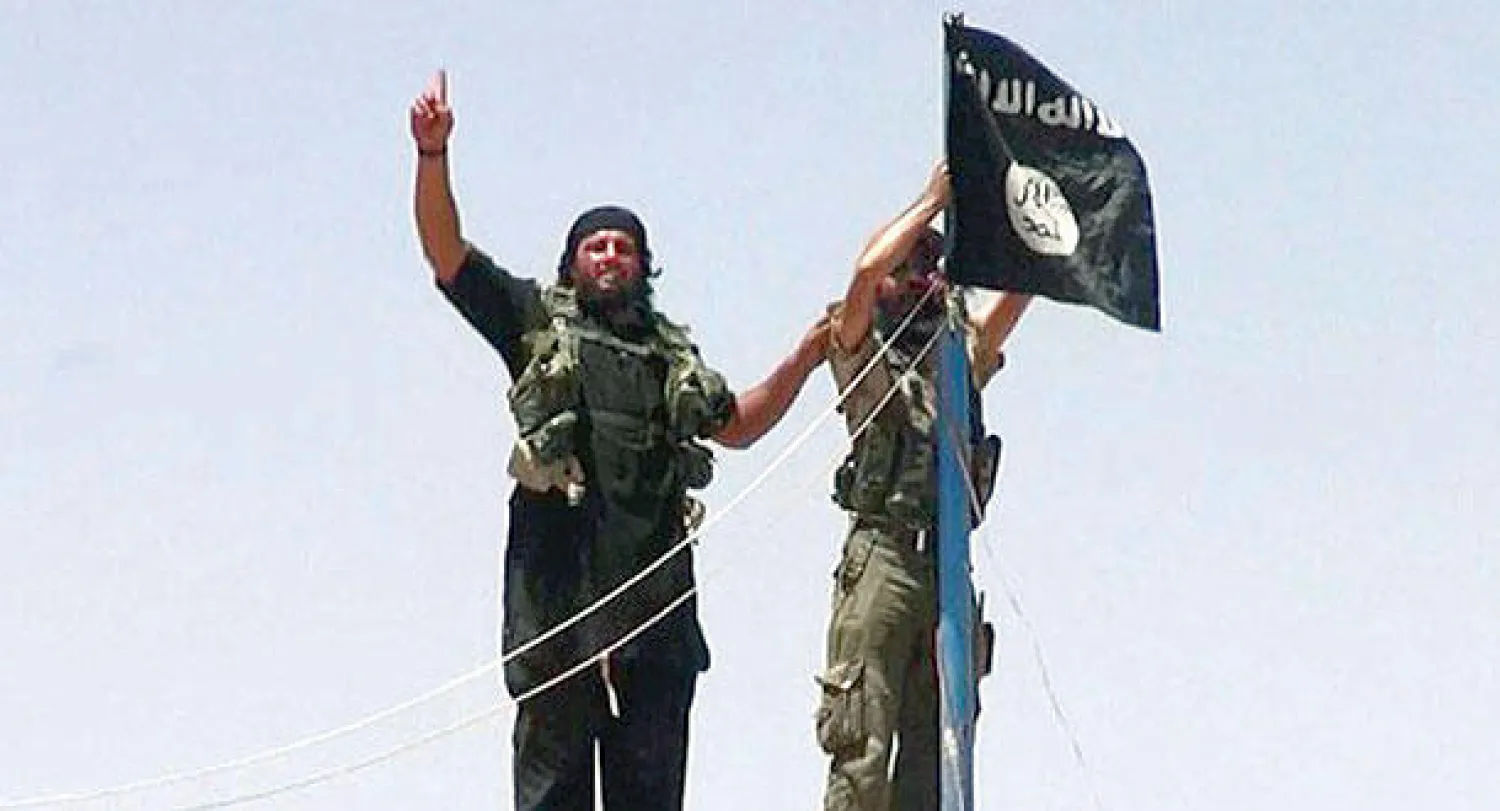صورة أرشيفية لعنصرين من تنظيم داعش يرفعان علم التنظيم في مدينة الموصل العراقية (أ.ف.ب)