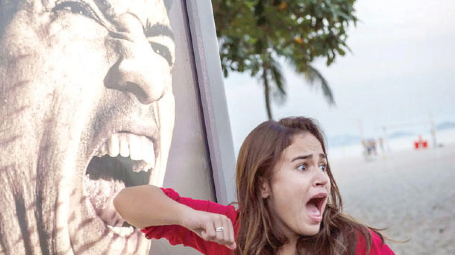 فتاه في صورة ساخرة أمام ملصق إعلاني لسواريز يهم بعضها في ريو دي جانيرو (أ.ف.ب)