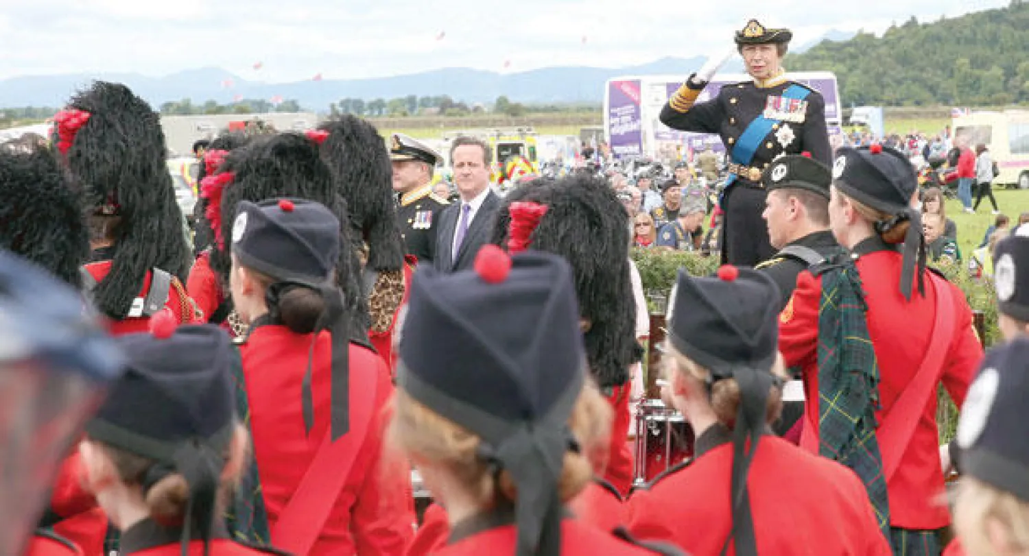 الأميرة آن ابنة ملكة بريطانيا توجه تحية بينما يبدو رئيس الوزراء ديفيد كاميرون (وسط خلف) ضمن الحضور خلال عرض عسكري بمناسبة «يوم القوات المسلحة» في مدينة ستيرلينغ باسكوتلندا أمس (إ.ب.أ)