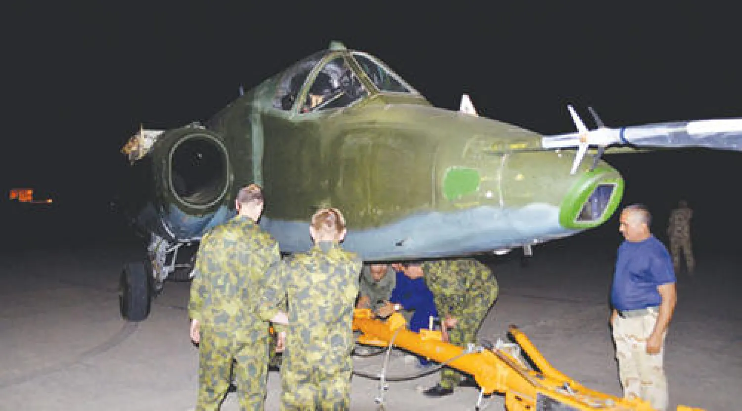 فنيون عراقيون وروس يعاينون طائرة سوخوي في مطار المثنى العسكري ببغداد أمس (أ.ب)