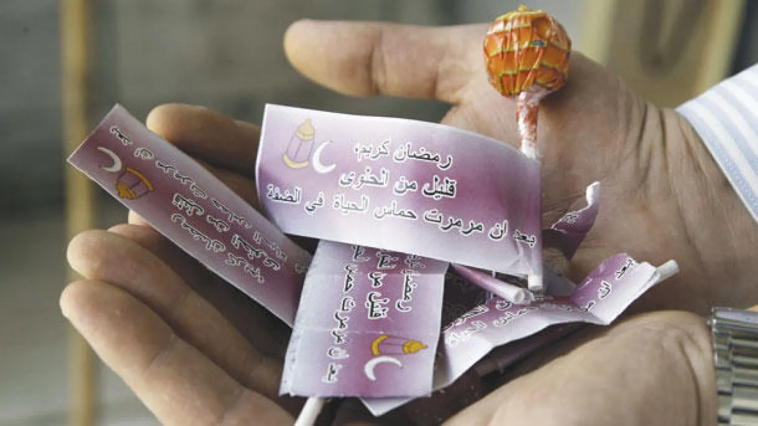 فلسطيني يعرض حلوى وزعتها السلطات الإسرائيلية، أمس، في مخيم بلاطة بالضفة الغربية، كُتبت عليها عبارات تندد بحماس (أ.ف.ب)