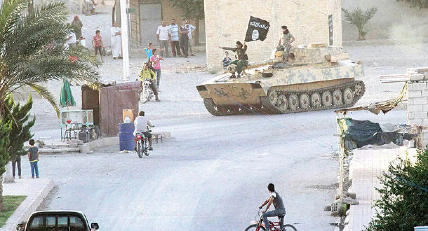 صورة وزعت أمس لعناصر تنظيم «داعش» على متن دبابة في مدينة الرقة (رويترز)