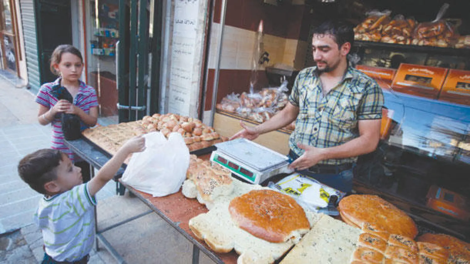 صبي سوري يشتري الخبز قبل حلول موعد الإفطار في حلب أمس (رويترز)