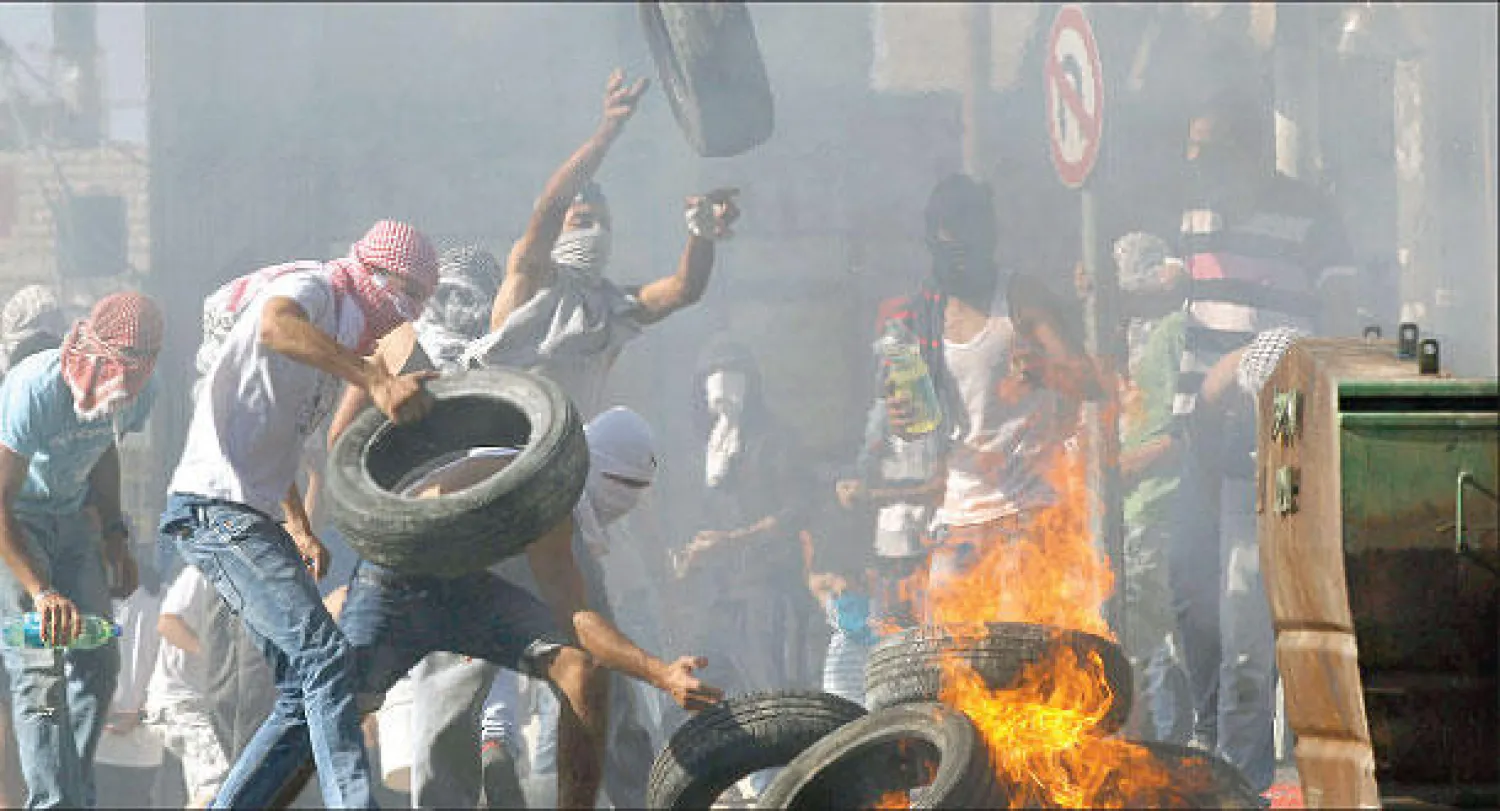 فلسطينيون يحرقون إطارات سيارات خلال مواجهات مع القوات الإسرائيلية في القدس اندلعت أمس بعد قتل مستوطنين فتى فلسطينيا (رويترز)