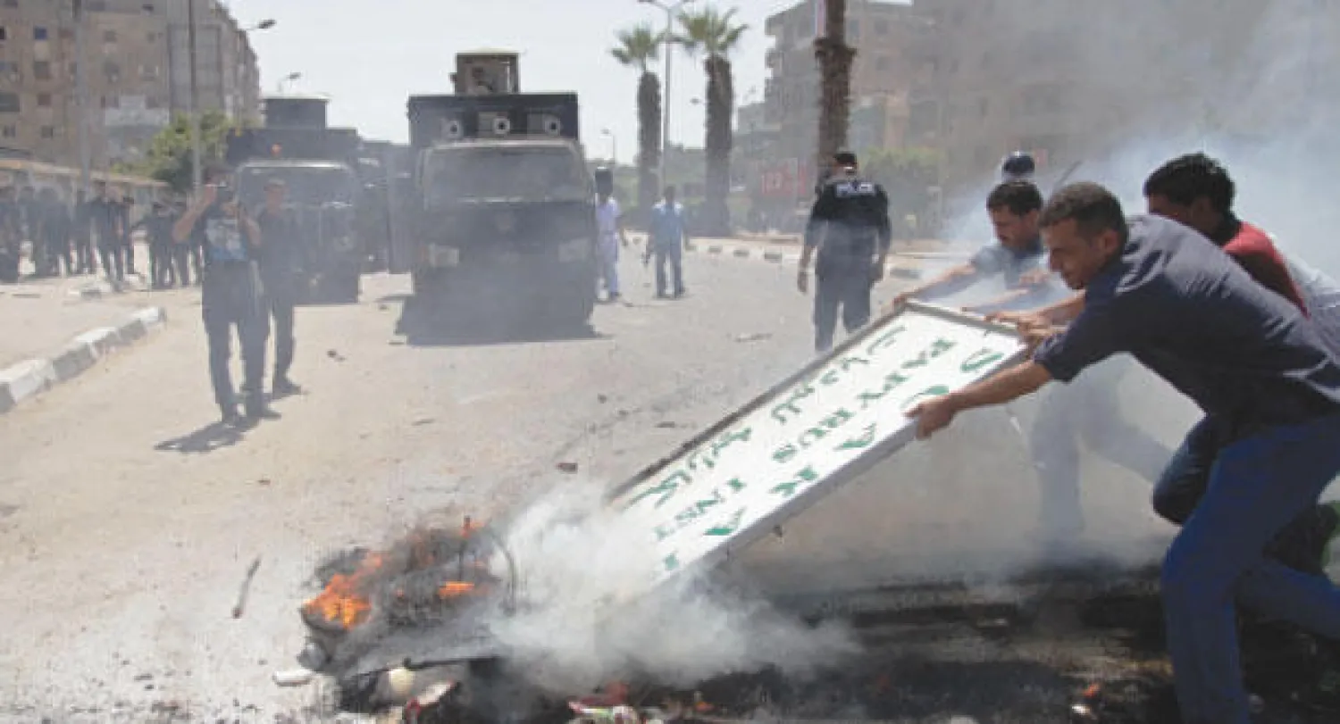 مواطنون يحاولون التخلص من حطام واجهة خشبية محترقة بعد أحداث عنف واشتباكات وقعت أمس في القاهرة بين قوات الأمن المصرية وأنصار الرئيس المعزول محمد مرسي (أ.ف.ب)