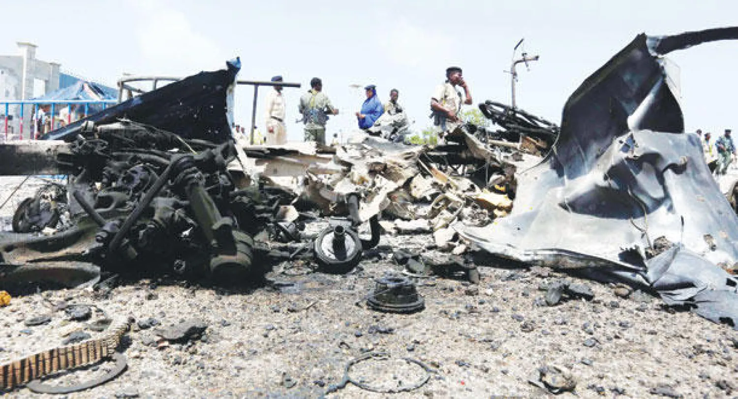 أفراد أمن صوماليون في موقع الحادث وسط حطام سيارة مفخخة انفجرت أمس بالقرب من مبنى البرلمان الصومالي في مقديشو (رويترز)