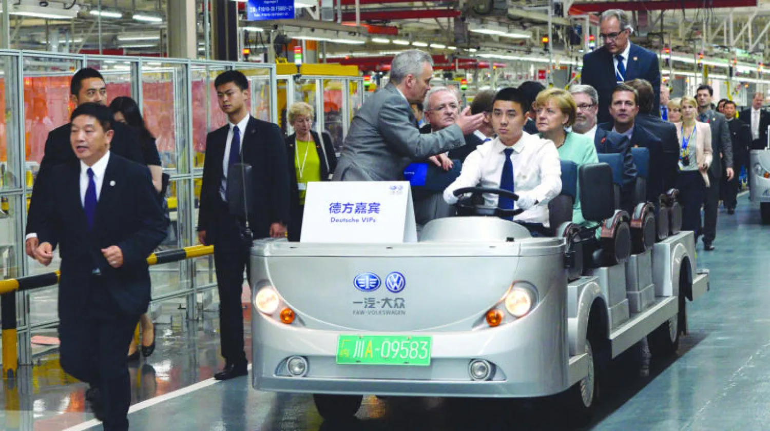 المستشارة الألمانية أنجيلا ميركل إلى جانب مسؤولين صينيين وألمان على متن عربة كهربائية في مصنع سيارات للمجموعة الألمانية فولكس فاغن بالشراكة مع شركة فاو الصينية (أ.ف.ب)
