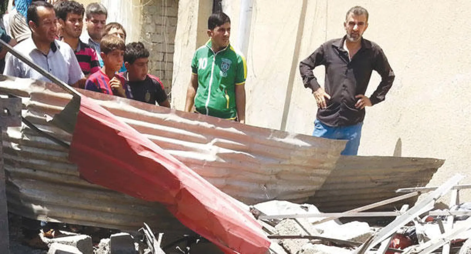 عراقيون يعاينون الأضرار التي خلفها قصف جوي في الموصل أمس (إ.ب.أ)