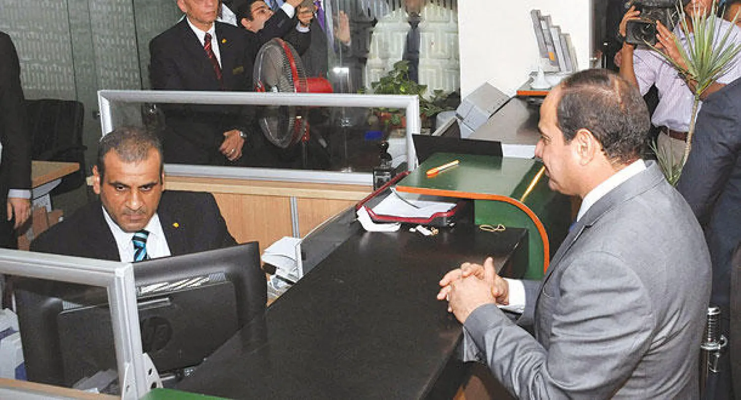 الرئيس المصري عبد الفتاح السيسي داخل فرع للبنك الأهلي في القاهرة وهو يقدم تبرعا ماليا لصالح صندوق «تحيا مصر» أمس (إ.ب.أ)