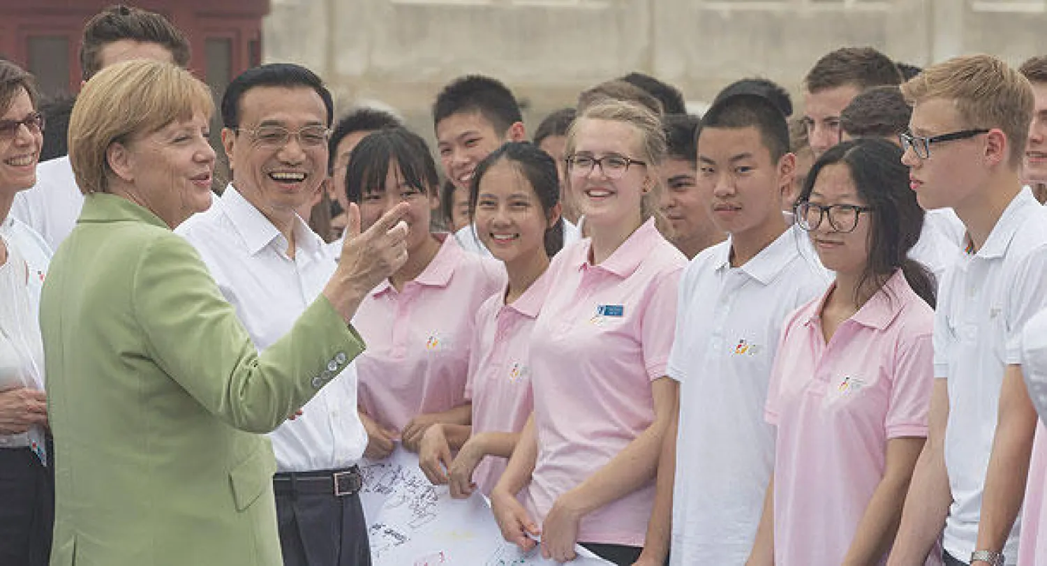 المستشارة الألمانية أنجيلا ميركل ورئيس وزراء الصين لي كه تشيانغ يتجاذبان أطراف الحديث مع مجموعة  من طلبة مدارس اللغات الثانوية خلال لقائهما في معبد السماء في العاصمة بكين أمس (إ.ب.أ)