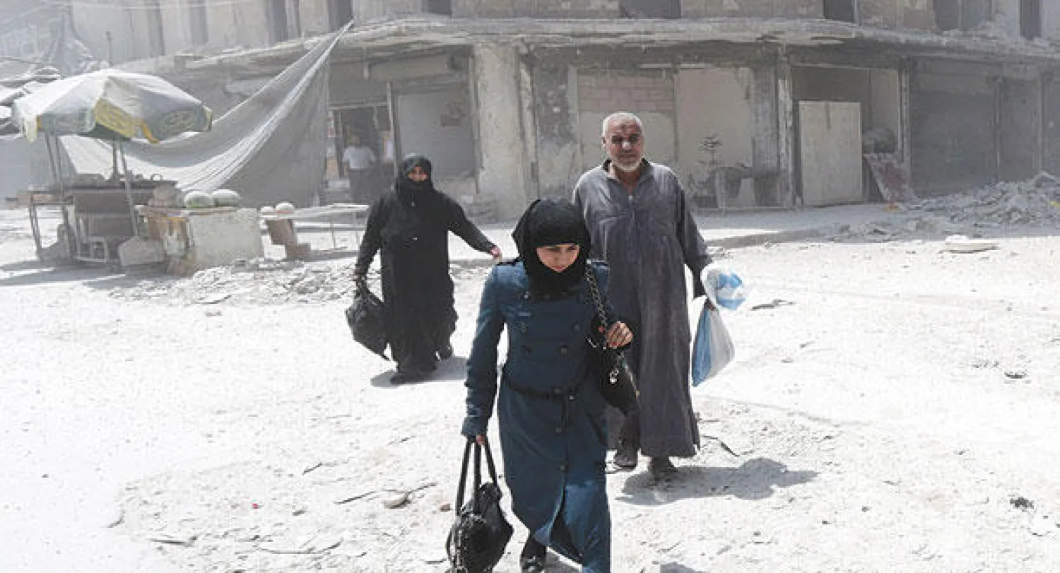 سوريون يغادرون منطق ة طريق الباب في حلب بعد إحدى الغارات بالبراميل المتفجرة على المدينة المهددة بالحصار (أ.ف.ب)