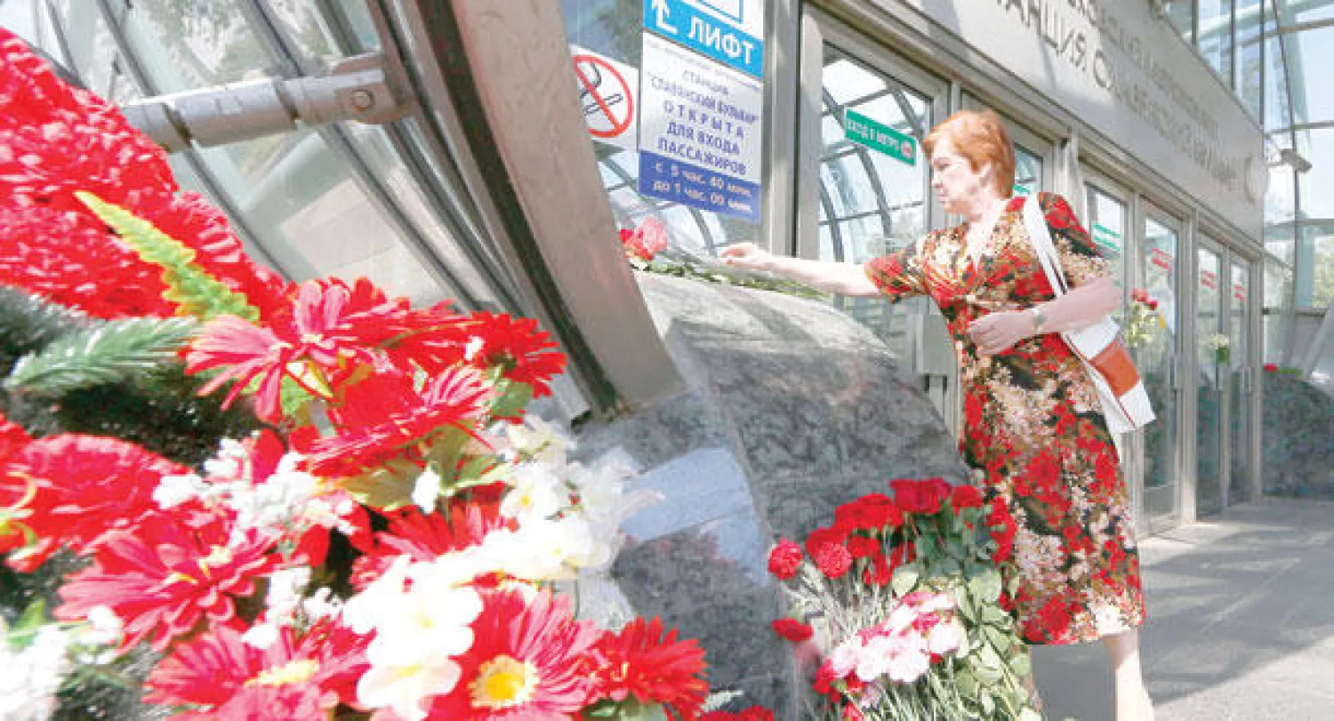 امرأة تضع وردا أمام مدخل إحدى محطات مترو موسكو أمس لتذكر الضحايا (إ.ب.أ)