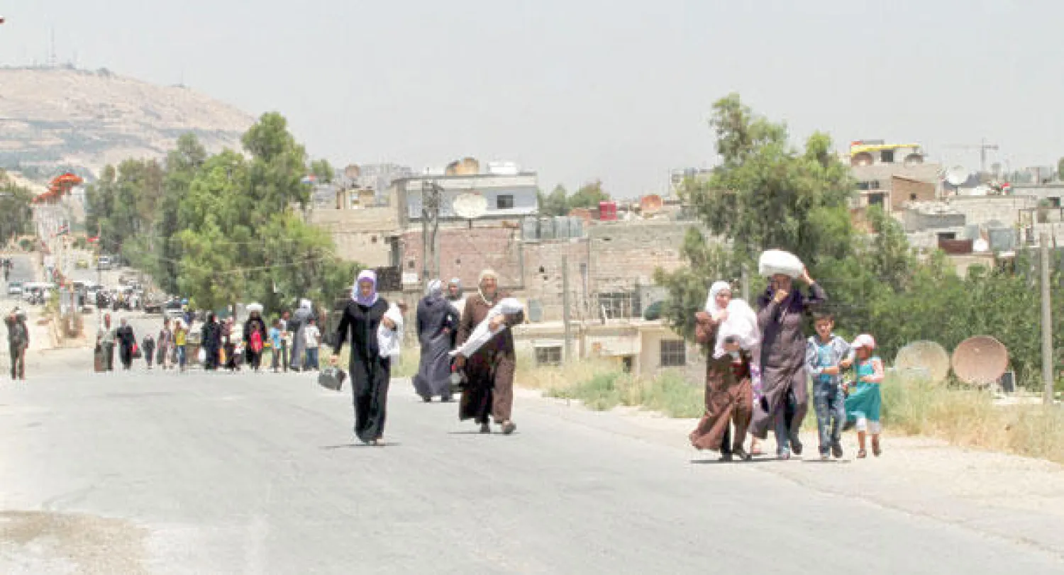 سوريون عائدون إلى المعظمية في ريف دمشق حاملين أغذية تسلموها كمساعدات من الصليب الأحمر تحت إشراف الأمم المتحدة وبالتنسيق مع النظام السوري أمس (أ.ب)