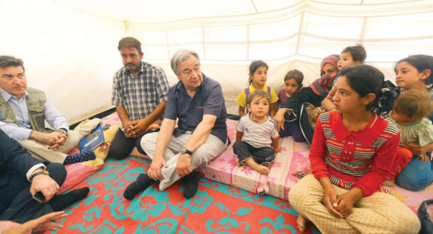 المفوض السامي لشؤون اللاجئين أنطونيو غوتيريس مع مجموعة من الأطفال المهجرين مع عوائلهم في مخيم خازر قرب أربيل (إ.ب.أ)