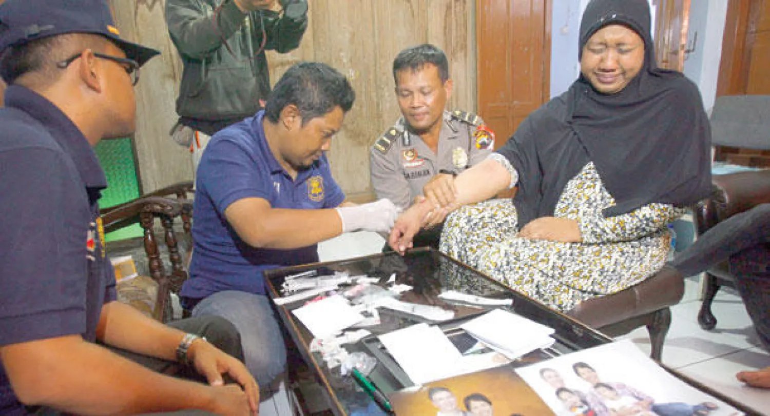 ضباط شرطة يأخذون عينة حمض نووي من عيدة ماردياتي شقيقة يولي هاستيني إحدى ضحايا الطائرة في سولو بجزيرة جاوة الإندونيسية أمس. وكانت يولي وزوجها واثنان من أولادهما على متن الطائرة المنكوبة (إ.ب.أ)