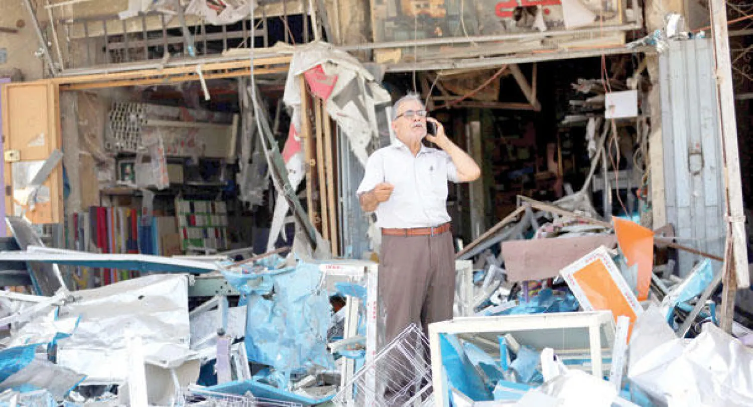 عراقي يتحدث بالهاتف الجوال وسط أنقاض خلفها انفجار سيارة مفخخة في حي الجهاد غرب بغداد أمس (أ.ب)