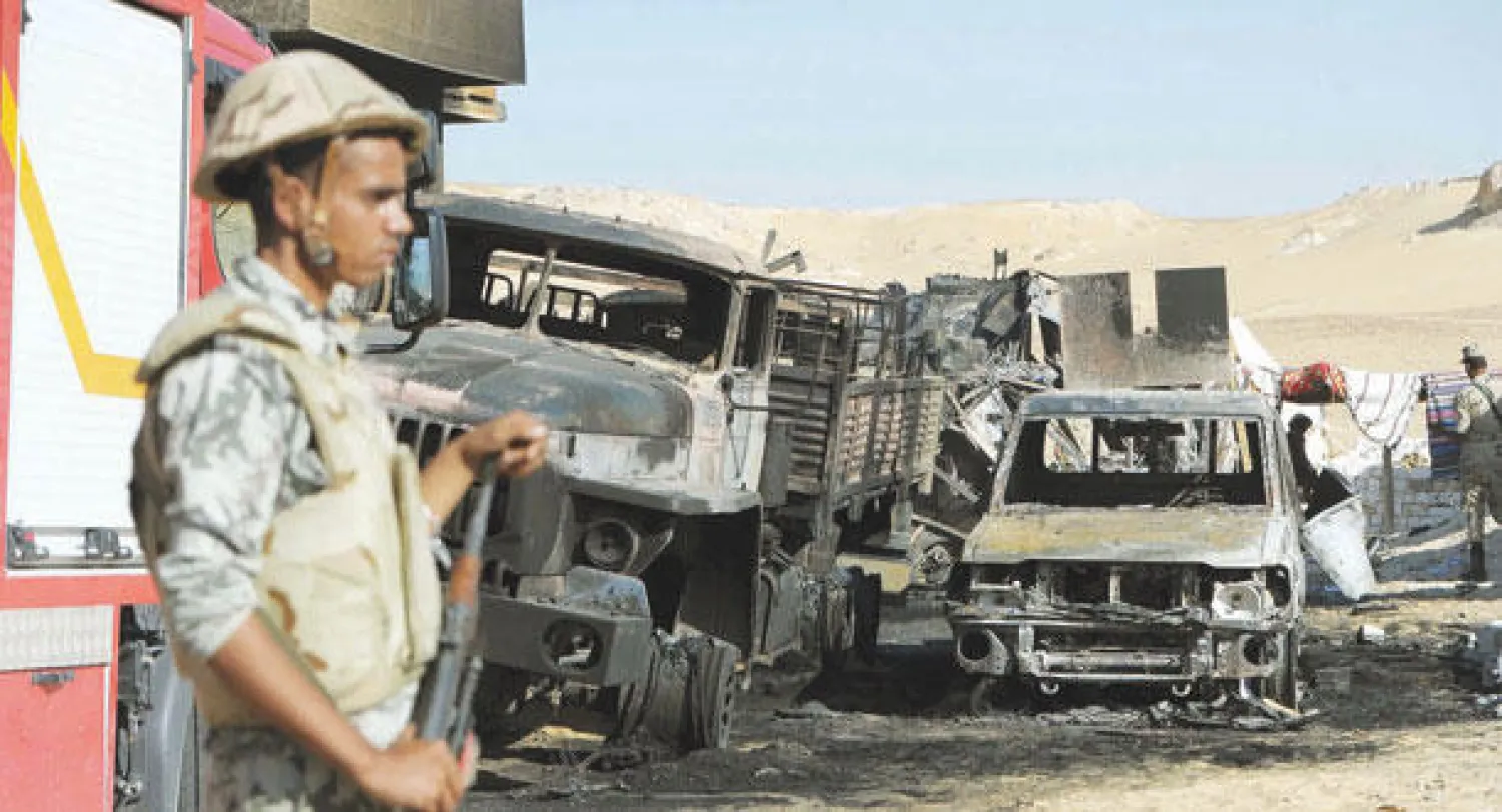 جندي مصري بجوار آليات عسكرية محترقة ومدمرة بعد الهجوم الإرهابي على كمين الفرافرة (إ.ب.أ)