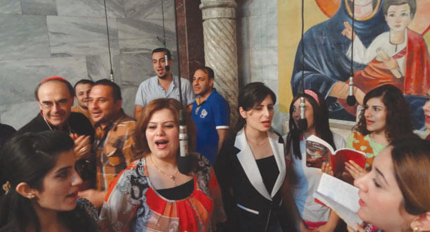 الكاردينال الفرنسي فيليب بربران رئيس أساقفة ليون يؤدي أناشيد دينية مع مسيحيين عراقيين في كنيسة بكركوك شمال العراق (أ.ف.ب)