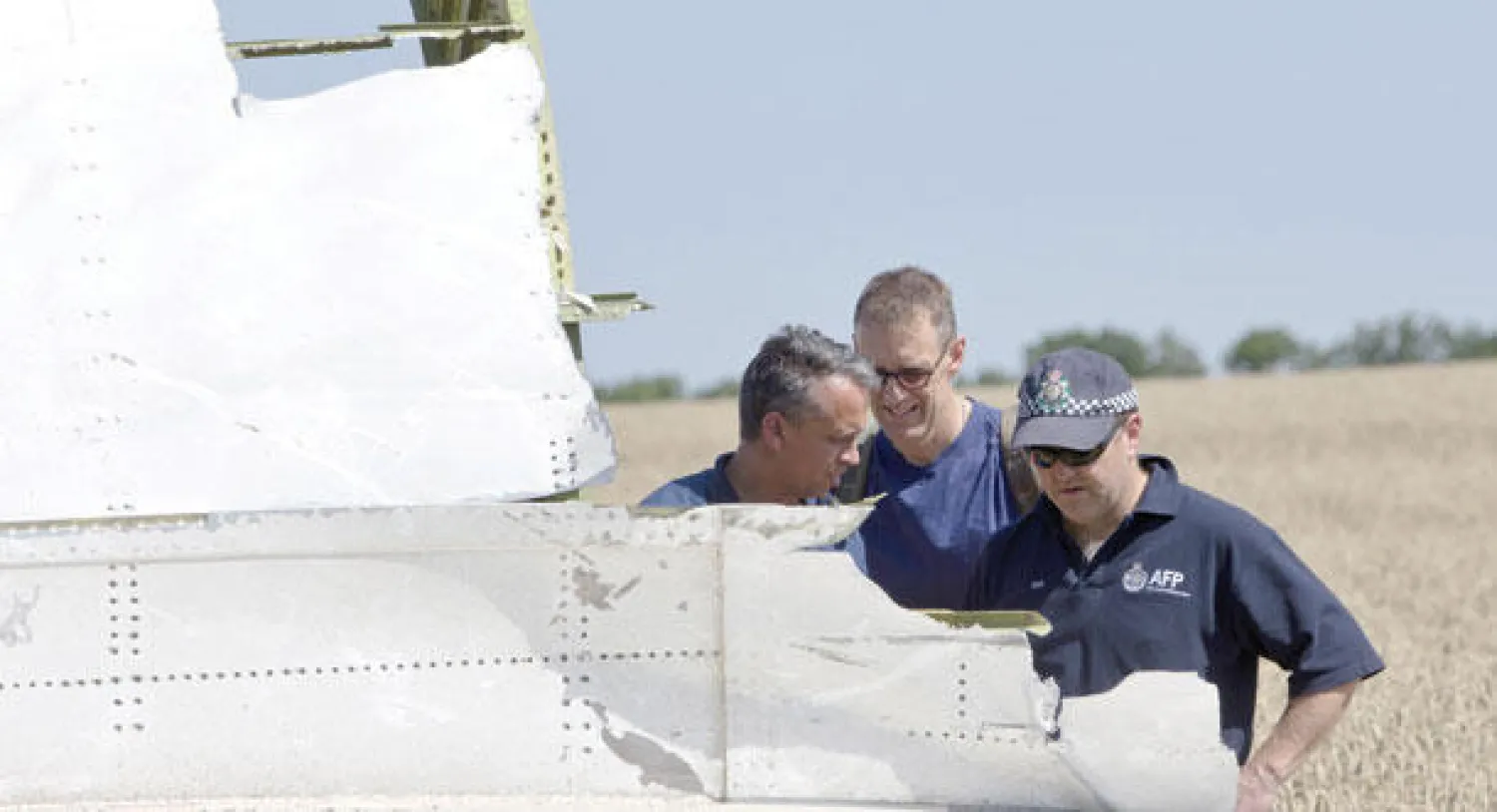 خبراء من أستراليا وهولندا يفحصون قطعة من الطائرة المحطمة  في منطقة دونيستك بشرق أوكرانيا أمس (أ.ب)