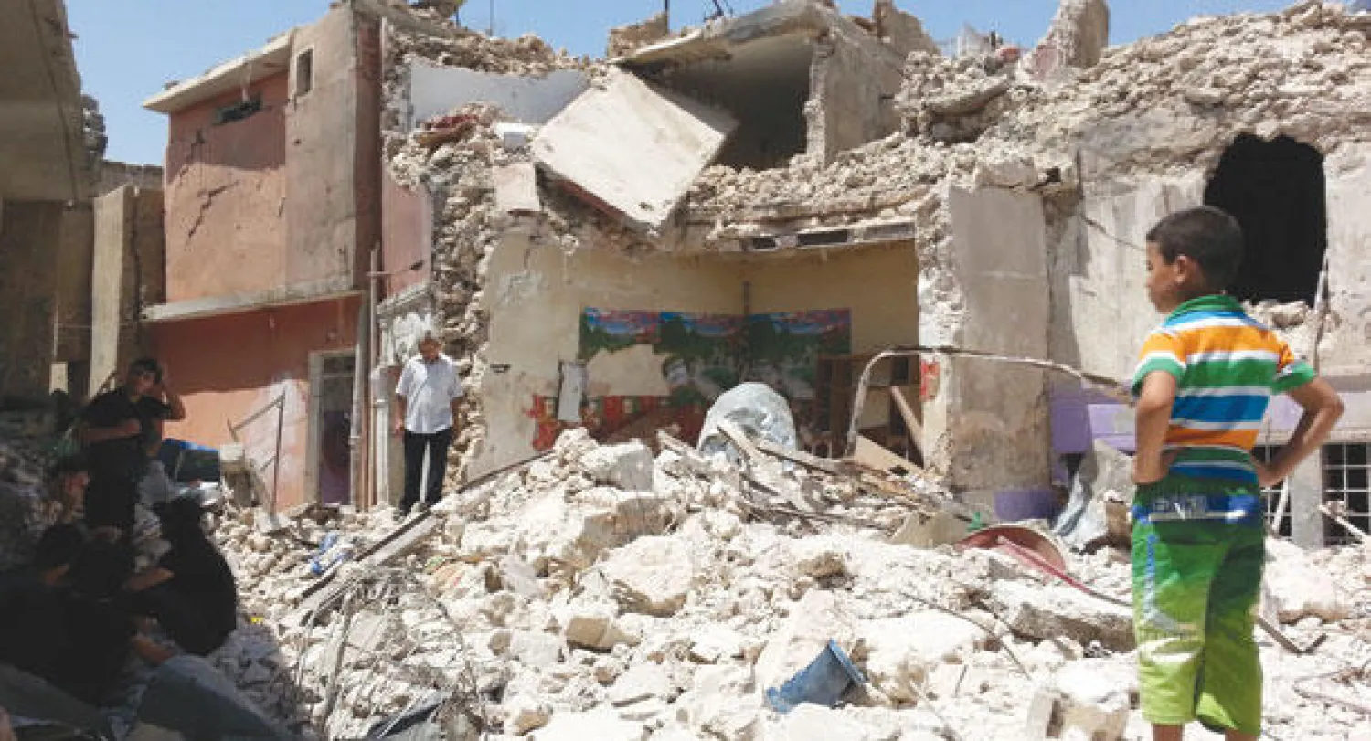 عراقيون يعاينون الدمار الذي خلفه قصف لطيران الجيش في الموصل أمس (إ.ب.أ)