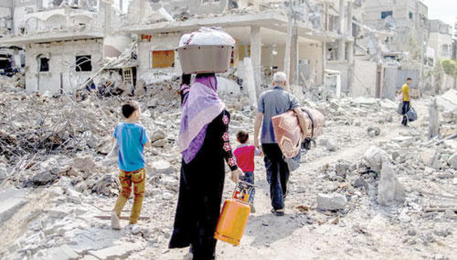 عائلة فلسطينية عائدة إلى بيتها الذي دمرته القوات الإسرائيلية أمس (أ.ف.ب)