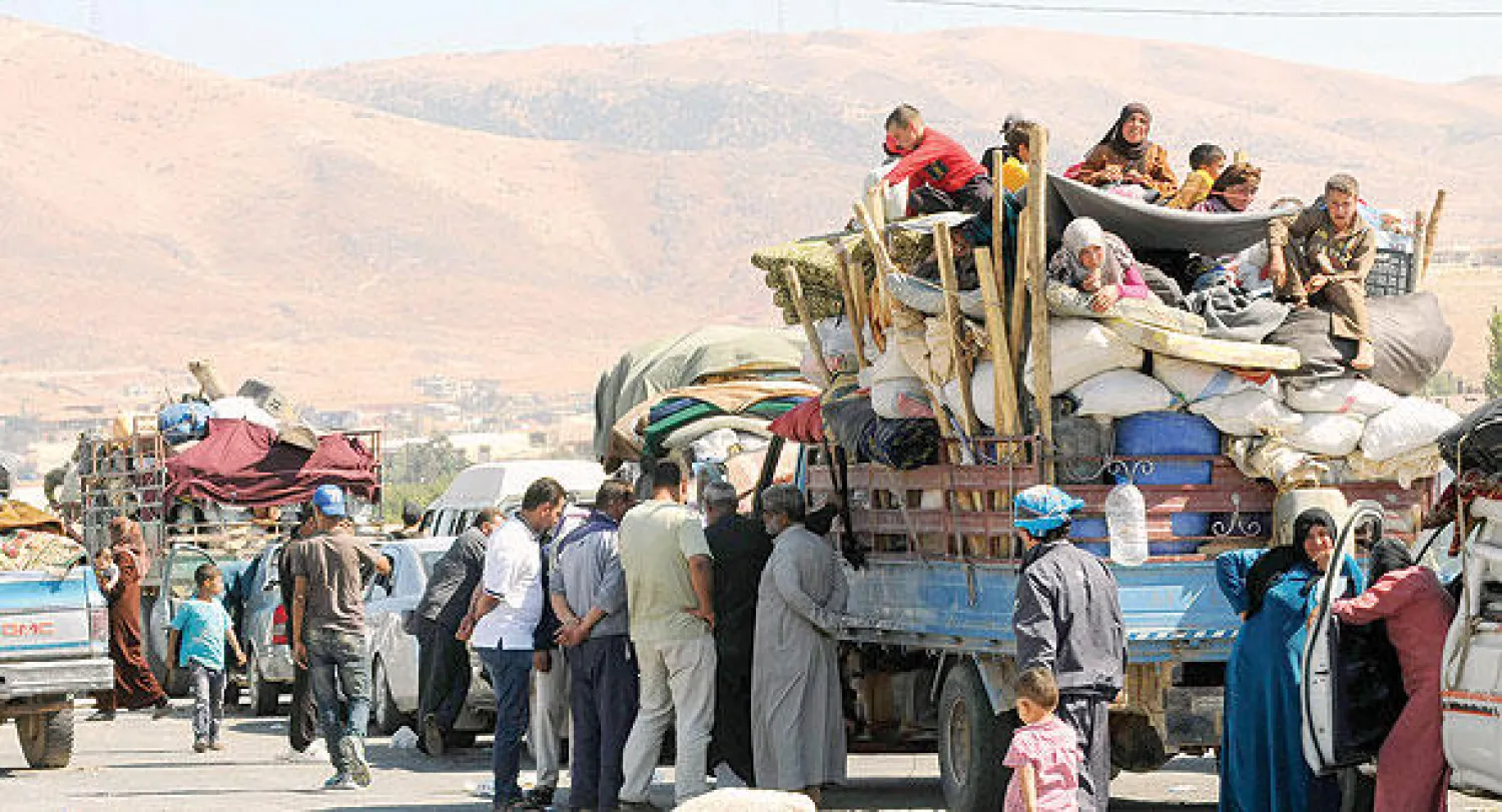 اللاجئون السوريون الذين فروا من القتال الأخير في عرسال ينتظرون داخل الشاحنات  في «مجدل عنجر» في سهل البقاع قرب الحدود اللبنانية مع سوريا (رويترز)