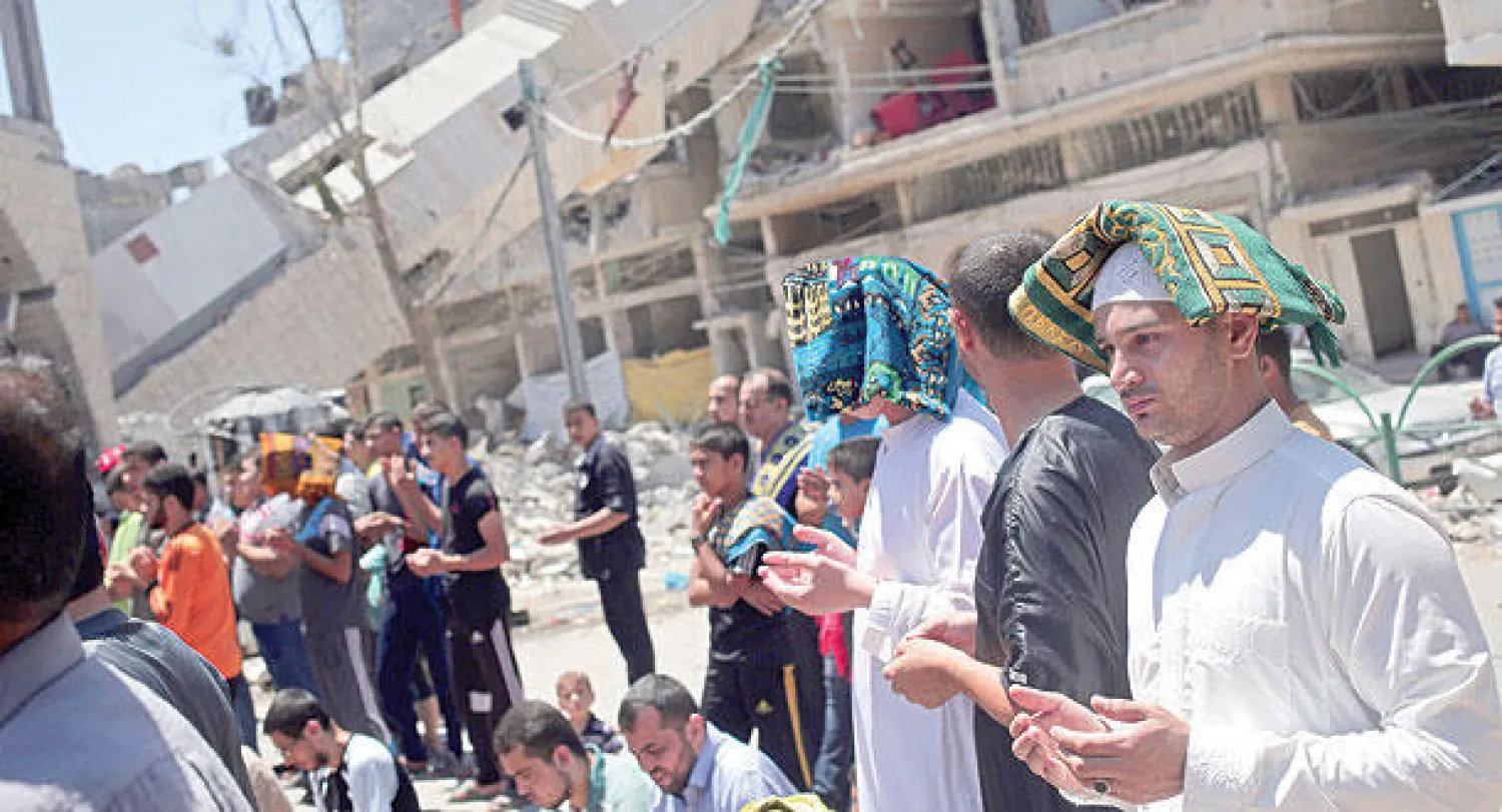 فلسطينيون يؤدون صلاة الجمعة أمام أحد المساجد الذي كان تعرض للقصف الإسرائيلي الأسبوع الماضي في غزة (أ.ب)