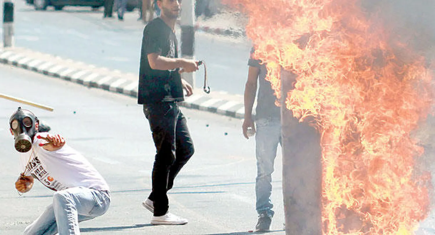 محتجون في الضفة الغربية لدى مواجهات مع عناصر من الجيش الإسرائيلي أمس (أ.ف.ب)