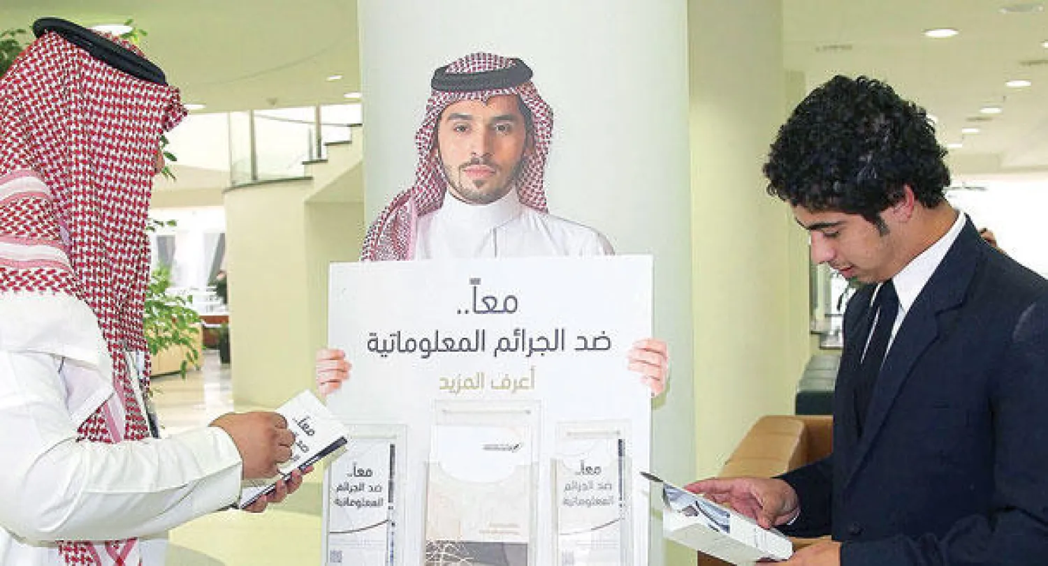 مواطنان يطلعان على قوانين نظام مكافحة جرائم المعلومات في معرض تجاري (تصوير: خالد الخميس)