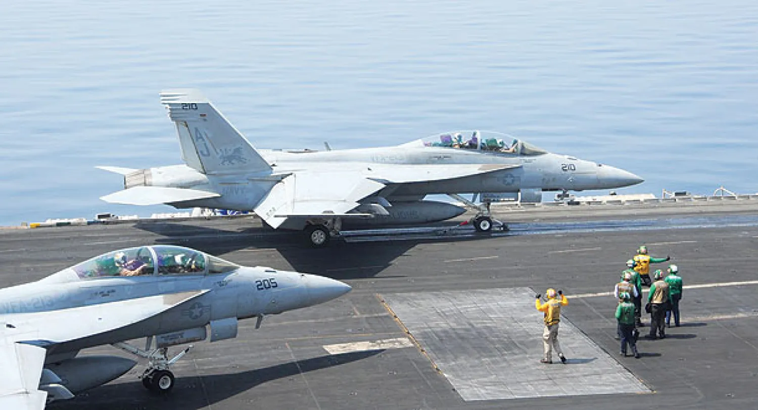 جندي في البحرية الأميركية يوجه طائرة مقاتلة من نوع «أف 18» سوبر هورنيت تقلع من حاملة الطائرات «يو إس إس إتش دبليو جورج بوش» لضرب مواقع «داعش» في شمال العراق أمس (أ.ف.ب)